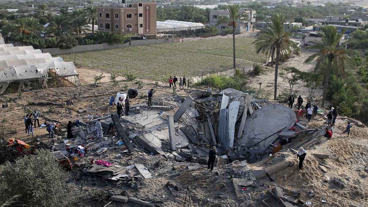 Palestinians gather around the remains of a house destroyed in an Israeli air strike in the southern Gaza Strip