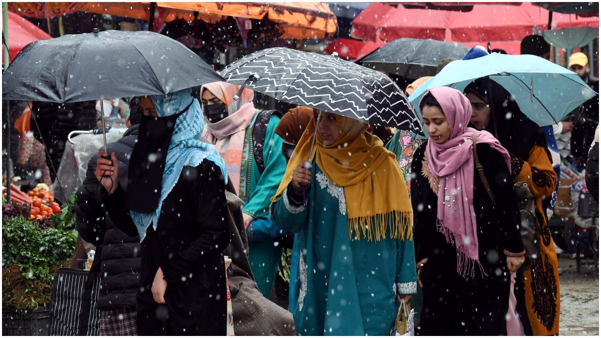 People carrying umbrellas walk amid fresh snowfall in Srinagar