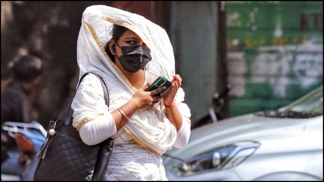 A girl uses a scarf to protect herself from the heat. (ANI) A girl uses a scarf to protect herself from the heat