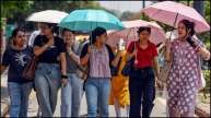 Students use umbrellas to shield from the scorching sun