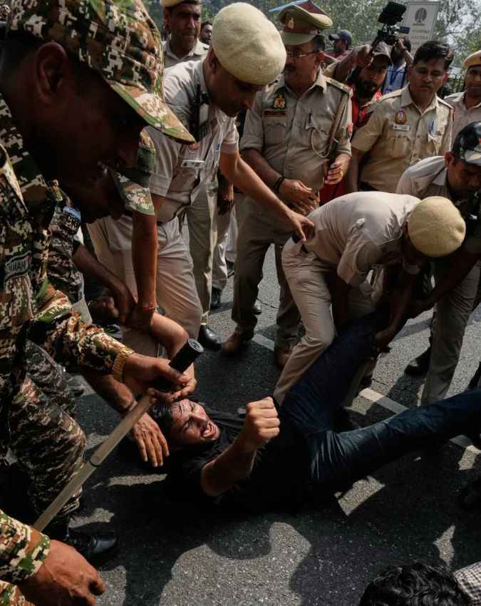 सड़क पर प्रदर्शनकारी को हिरासत में लेती पुलिस